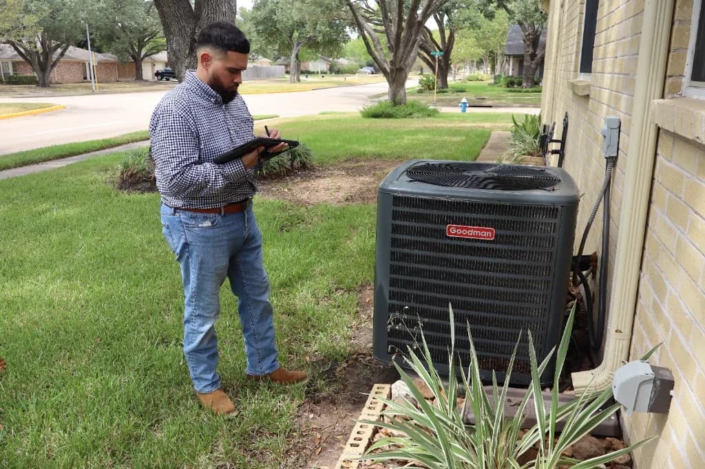 Luis Salas inspecting an outdoor air conditioner with a tablet
